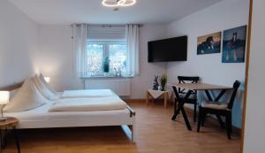 a bedroom with a bed and a table and a tv at Dorfschänke DEGGENDORF Hotel & Apartmenthaus in Deggendorf