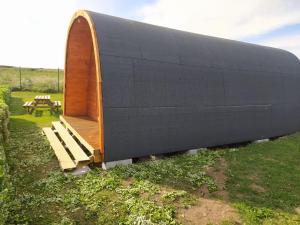 a large black building with a bench in a field at Bungalow 3 personas - Camping Playa de Tapia in Tapia de Casariego +2 photos