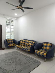 a living room with two couches and a ceiling fan at Yasmeen Homestay Kijal Nenas 2 in Kijal