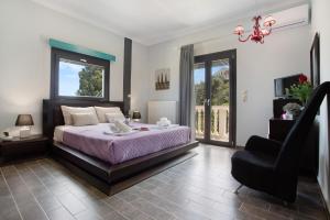 a bedroom with a bed and a chair and windows at Zante Sunset Vibes Luxury Villa in Áno Yerakaríon