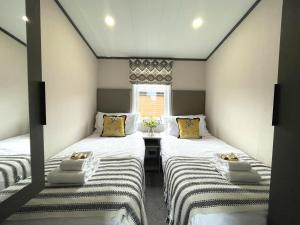 two twin beds in a small room with a window at Beautiful Luxury Lakeside Lodge Hot Tub Views Pass the Keys in Annan