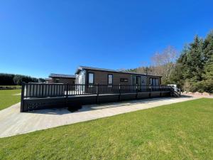 a house with a fence in the middle of a field at Beautiful Luxury Lakeside Lodge Hot Tub Views Pass the Keys in Annan