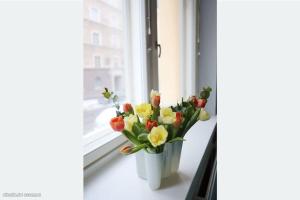 Corner apartment في هلسنكي: مزهرية من الزهور تقف على حافة النافذة