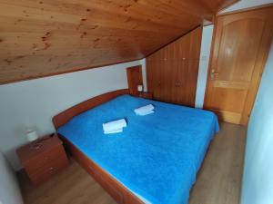 a small bedroom with a blue bed with a wooden ceiling at Dario studio apartman in Kukljica