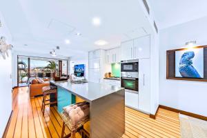 a kitchen and living room with white cabinets and a counter at Absolute Luxury Marina Lifestyle at The Port of Airlie Beach in Airlie Beach