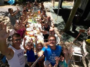 a group of people sitting around a table with their hands up at Camping Ancora in Comacchio