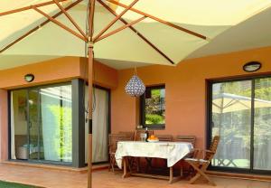 een eetkamer met een tafel en een paraplu bij Pretty garden apartment next to a charming beach in Lloret de Mar