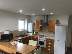 a kitchen with a wooden table and a white refrigerator at Dovedale Apartment in Moreton