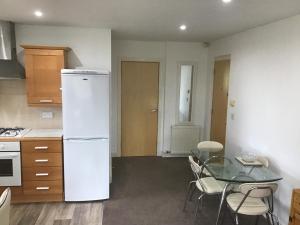 a kitchen with a white refrigerator and a glass table at Dovedale Apartment in Moreton