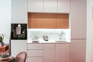 una cocina con armarios blancos y fregadero en JU3 Apartments, en Liubliana
