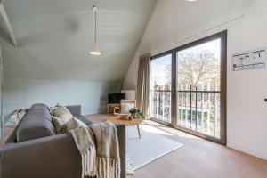 een woonkamer met een bank en een groot raam bij Bonrepo Room 105 in Brugge