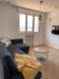 a living room with a couch and a table at MyHouseSpain - Ático con terraza en la playa in Gijón