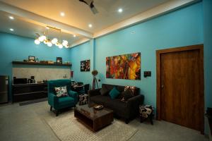 sala de estar con paredes azules, sofá y sillas en Barefoot Homestays, en Rāmnagar