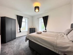 a bedroom with a large bed and two windows at Large house on the edge of the Brecon Beacons in Beaufort