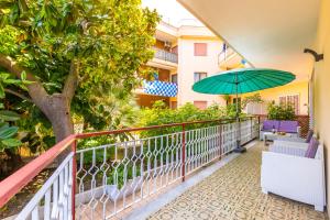 a balcony with a green umbrella and chairs at Il Riccio di Mare a 5 minuti da Sorrento in Sant'Agnello