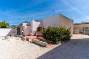 Uma casa branca com um banco vermelho à frente. em Casa Vacanza Lu Mare e Lu Ientu em Casamassella