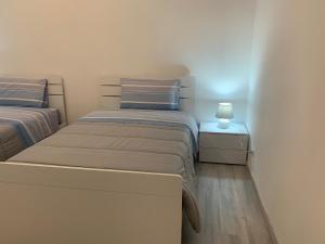 twee bedden in een slaapkamer met een lamp op een nachtkastje bij La Fortuna in Quiliano