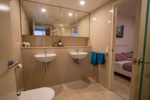 baño con 2 lavabos, cama y espejo en Darwin luxury apartment, en Darwin