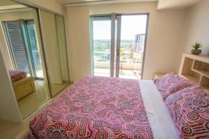 a bedroom with a large bed and a large window at Darwin luxury apartment in Darwin