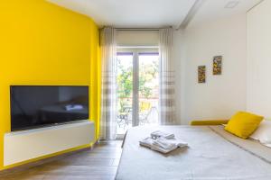 a bedroom with a yellow wall and a large flat screen tv at Il Riccio di Sole a meno di 5 minuti da Sorrento in Sant'Agnello