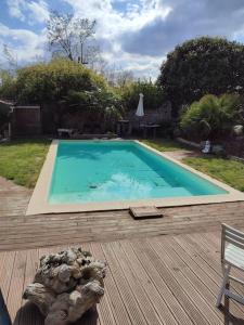 a swimming pool on a wooden deck with a bench and a chair at Maison Lavelanet de Comminges 