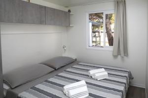 a bedroom with a bed with a striped blanket at Mobile home Istra BI VILLAGE in Fažana