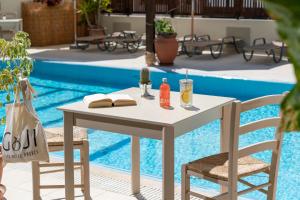 una mesa y dos sillas junto a una piscina en GOJI Vegan Hotel en Ialyssos
