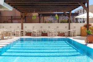 una piscina con mesas y sillas en un edificio en GOJI Vegan Hotel en Ialyssos