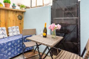 a table with a bottle of wine and flowers on a patio at Cute Fisherman's Cottage in the Heart of Brighton in Brighton & Hove
