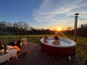 two people in a hot tub with the sunset in the background at Sol-flora in Tjele
