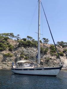a sailboat sitting in the water next to a hill at One day Sailing Tour San Teodoro Sardinia in Puntaldia