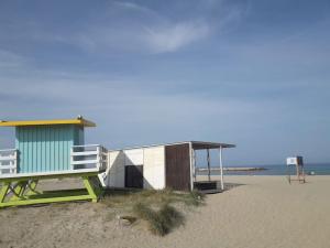 una cabaña en la playa y un banco en la playa en La maison coquillage, en Le Barcarès