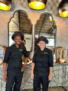 two people in black uniforms standing in a kitchen at Sambane Game Lodge 