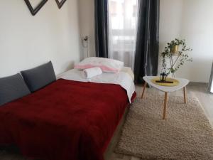 um quarto com uma cama com um cobertor vermelho e uma mesa em Apartman TONKOVIĆ em Imotski