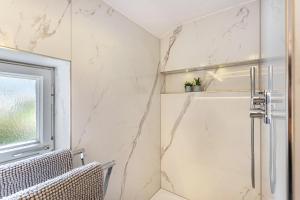 a bathroom with a shower with white marble walls at Haus Alpenveilchen - Appartement 1 in Schönau am Königssee