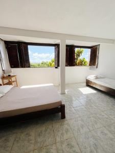 a bedroom with two beds and two windows at Morada Cacauêra in Itacaré