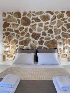 un letto con 2 cuscini e un muro di pietra di Marikos House, Pyrgaki Alyko Naxos a Spiaggia di Aliko
