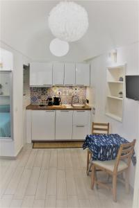 a kitchen with white cabinets and a table and a chair at La Maiolica in Anacapri