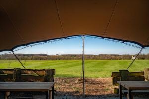 uma tenda com uma mesa e cadeiras e um campo em Wild Meadow, Lodge Farm, East Raynham em Fakenham