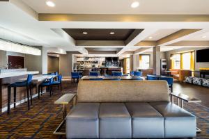 a lobby with a couch and tables and a bar at Sonesta Select Detroit Novi in Novi