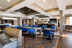 a dining room with tables and blue chairs at Sonesta Select Detroit Novi in Novi