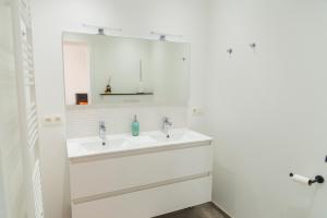 uma casa de banho branca com 2 lavatórios e um espelho em MAISON ROBERT em Modave