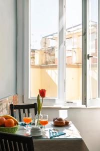 una mesa con una rosa roja y una ventana en Carafa Suite By Enjoy Napoli, en Nápoles