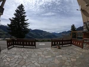 two benches on a patio with a tree and mountains at Auberge Le Valezan in Valezan