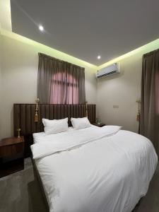 - une chambre avec un grand lit et des draps blancs dans l'établissement السلطان للشقق المفروشة, à Al-Ula