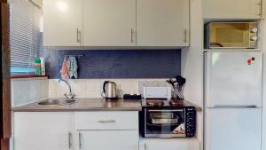 una pequeña cocina con fregadero y nevera. en San Lameer Villa 2516 by Top Destinations Rentals en Southbroom