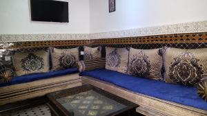 een woonkamer met een blauwe bank en een tv bij Dar Nour Fes in Fès