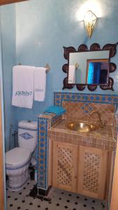 een badkamer met een wastafel, een toilet en een spiegel bij Dar Nour Fes in Fès