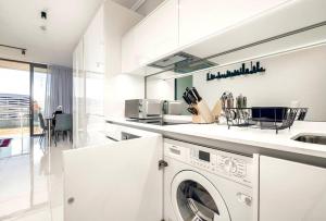 a white kitchen with a washing machine in it at Keza Cove at Waterfall Ellipse in Midrand