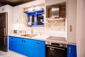 a kitchen with blue cabinets and a sink at Villa Rosemarie - Luxurious Villa with Pool Just Steps Away from the Sea By Villa Mana Gers in Psarou